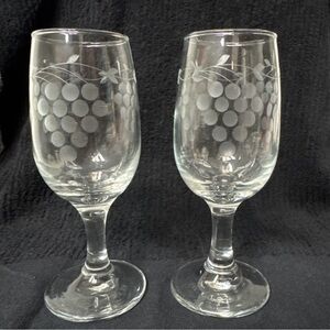 Two clear stemmed wine glasses with an acid-etched grape cluster/vine motif.